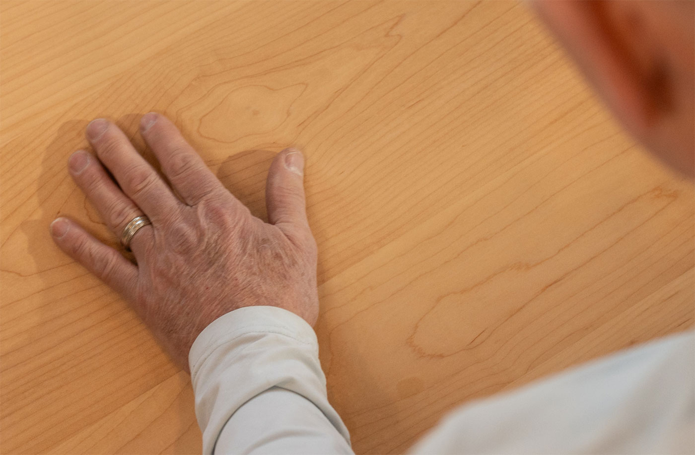 a man's hand rubbing a piece of smooth wood