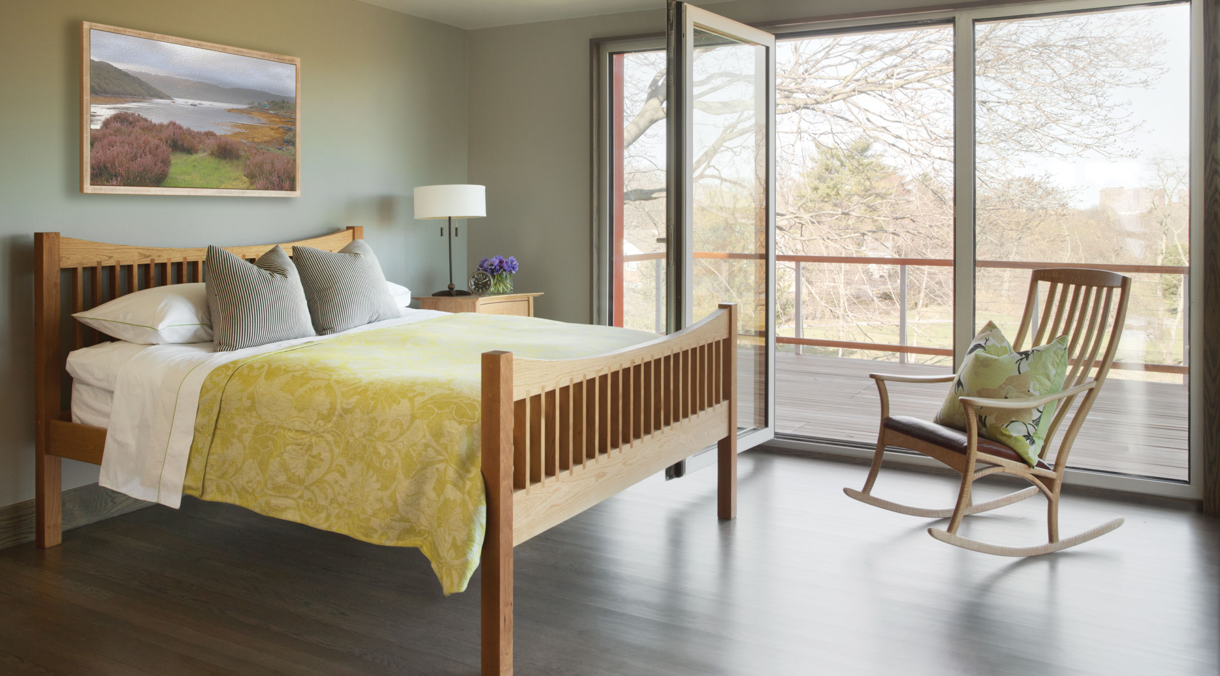 bedroom with rocker in front of slider onto a deck with a field behind