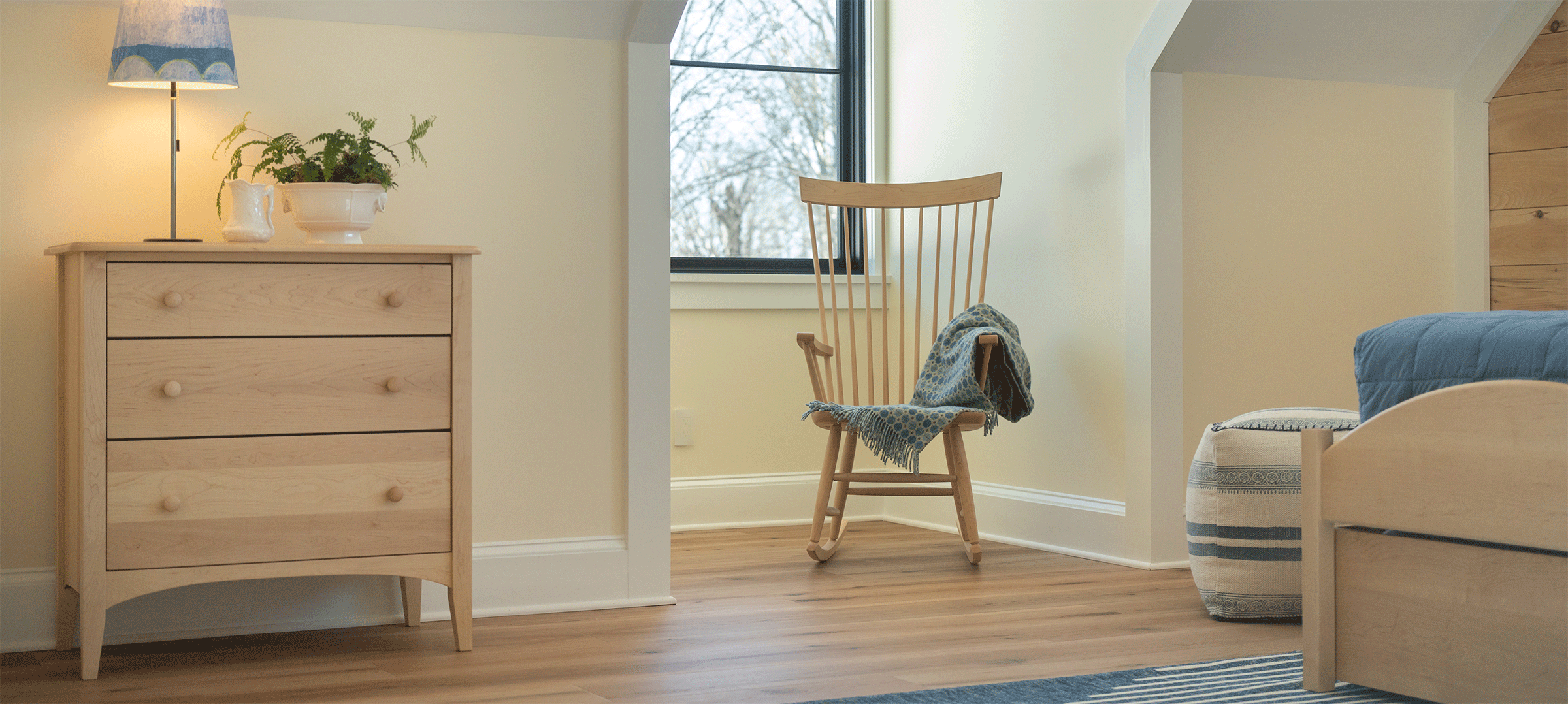 bedroom with rocker in a nook in front of a window and a small birch 3 drawer dresser
