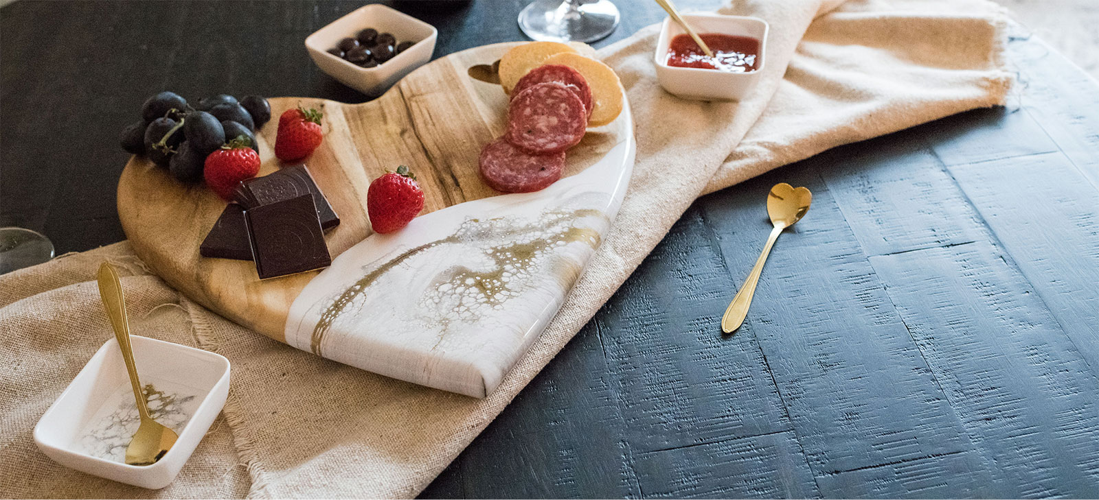 a hard shaped wood and resin cutting board with appetizers and sweet treats