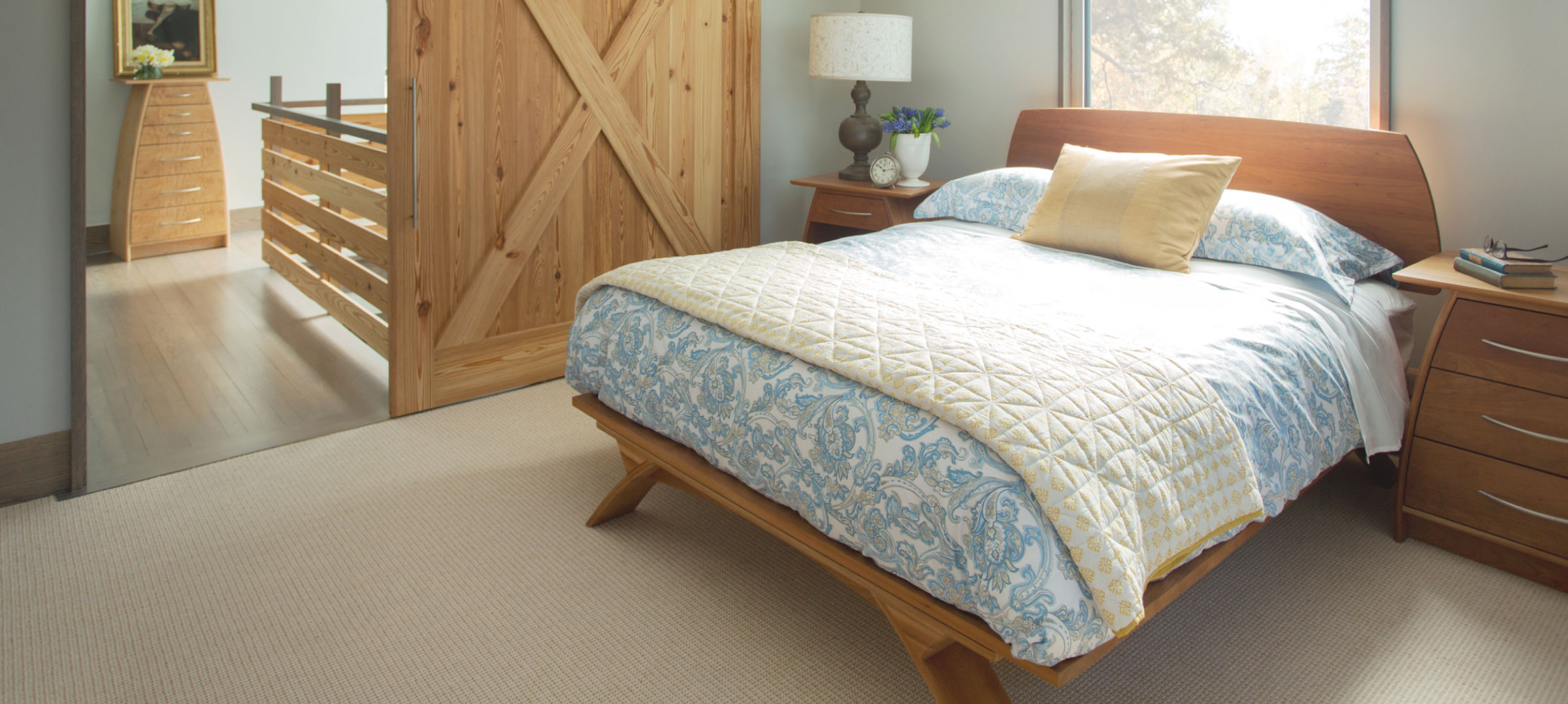 a cherry belmont bed and lingerie chest in the hallway through the sliding barn door