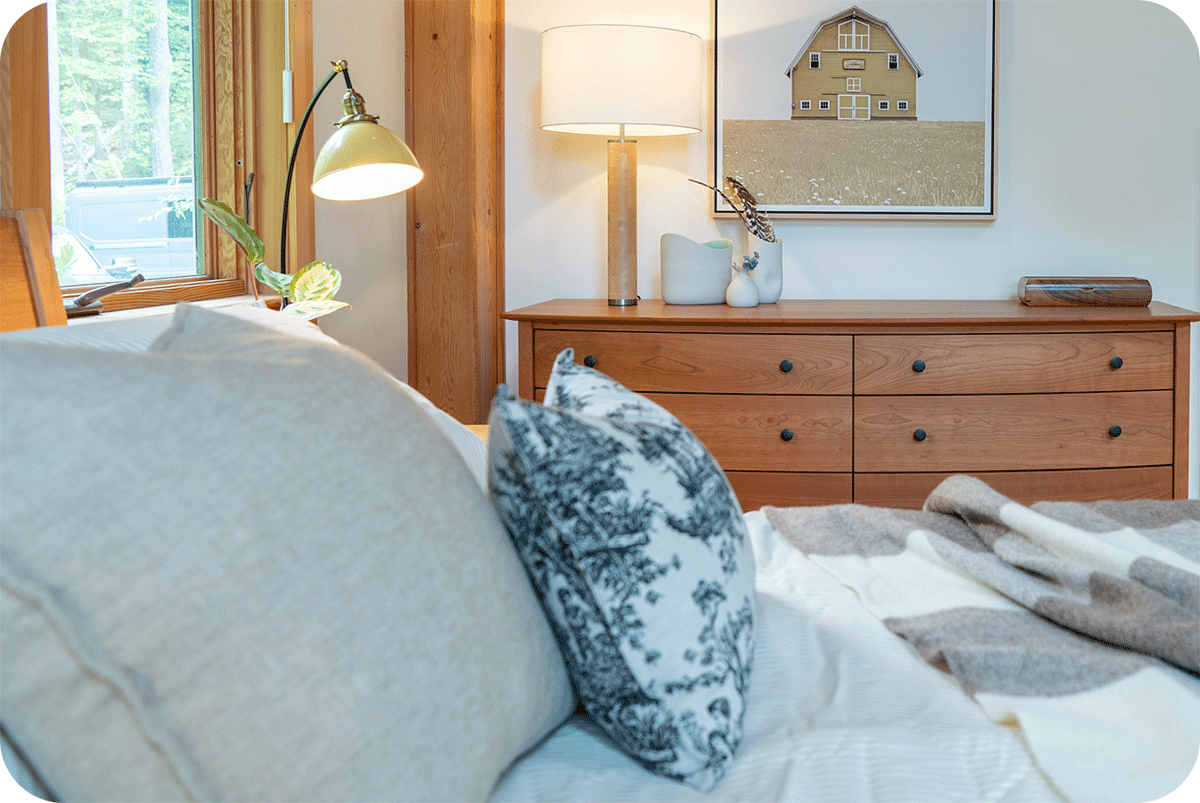 calm country style bedroom with a cherry dresser in the background