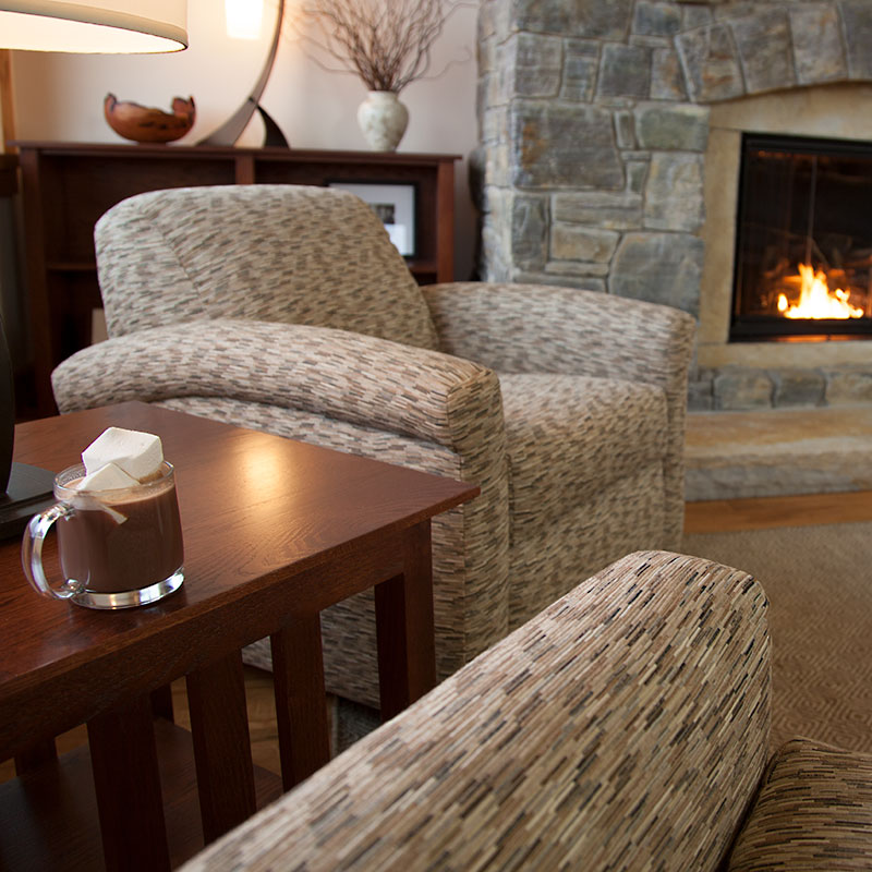 Comfy Living Room Setting with fully upholstered chairs, and a fire in the fireplace