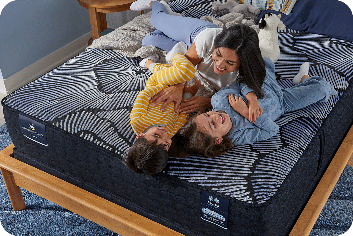 a mom playing with 2 kids on a bed