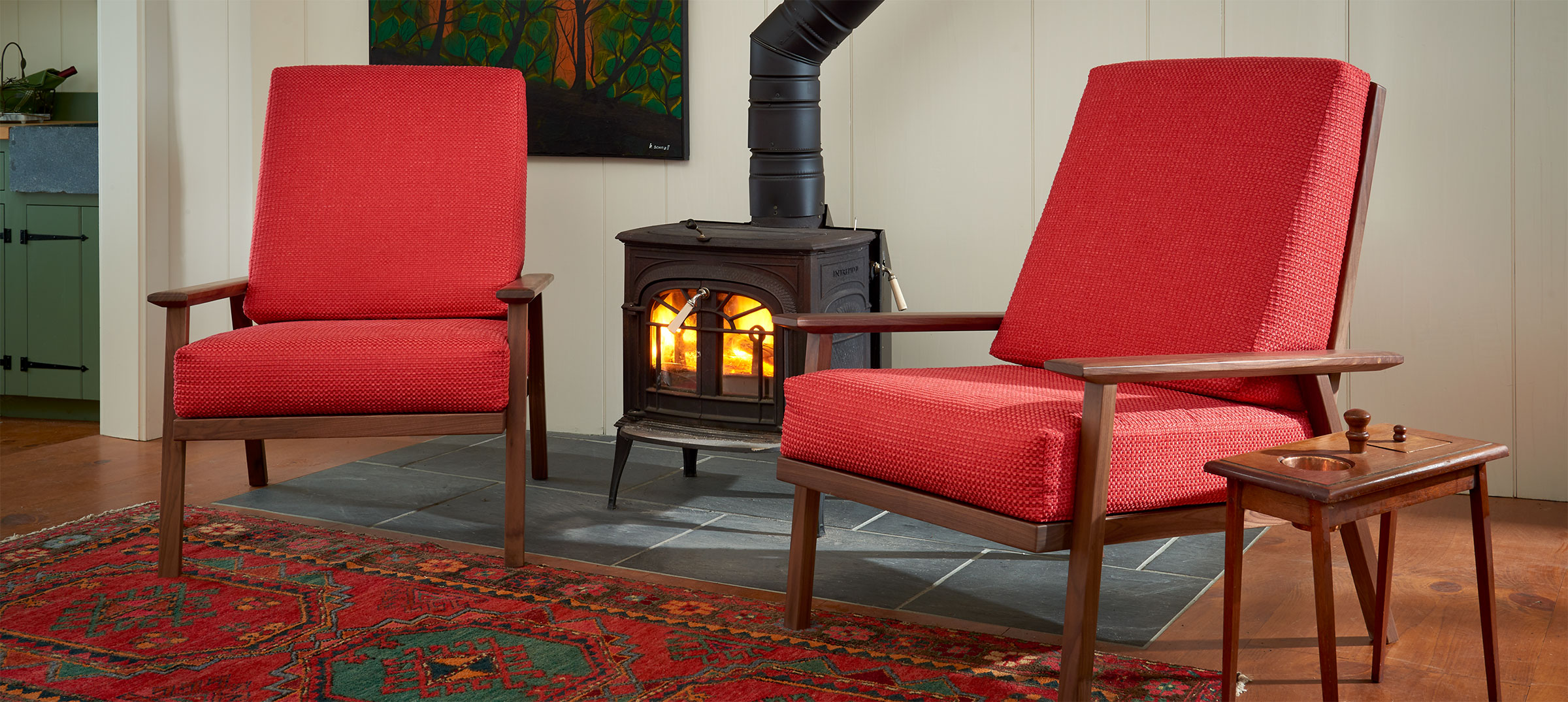2 modern wood framed westmore chairs in red fabric near a woodstove
