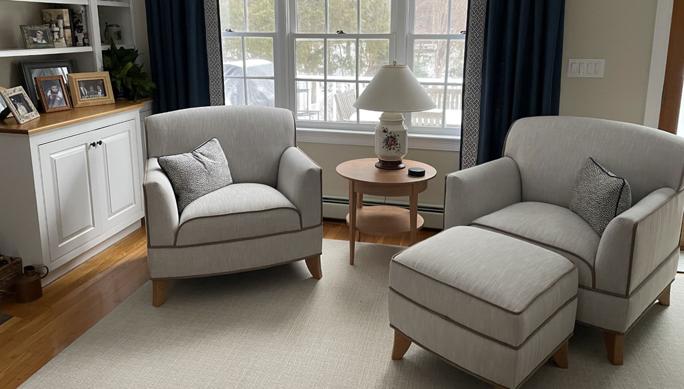 Living room setting featuring 2 Calais armchairs, a Calais ottoman and a Calais end table.