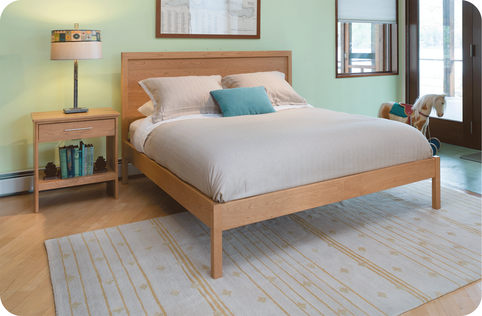 simple bed and nightstand with a rocking horse in the corner