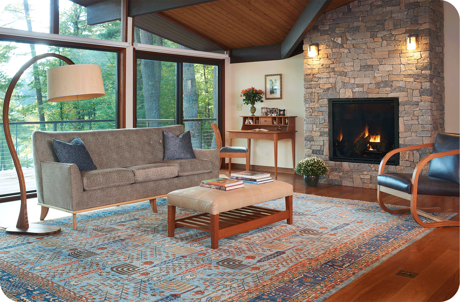 modern living room with fireplace and a wall of windows looking into the forest