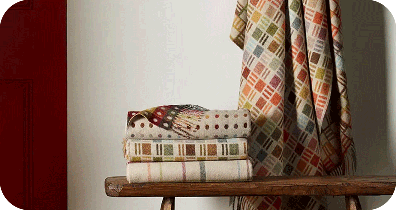3 folded wool throws, one hanging on the wall