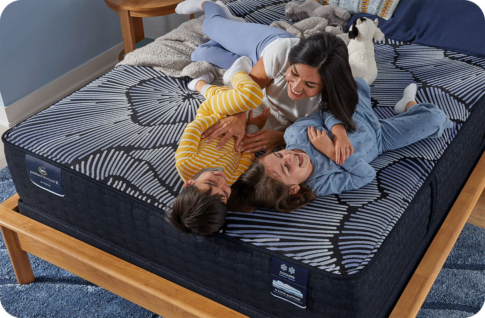 a mom and 2 kids playing on a bed