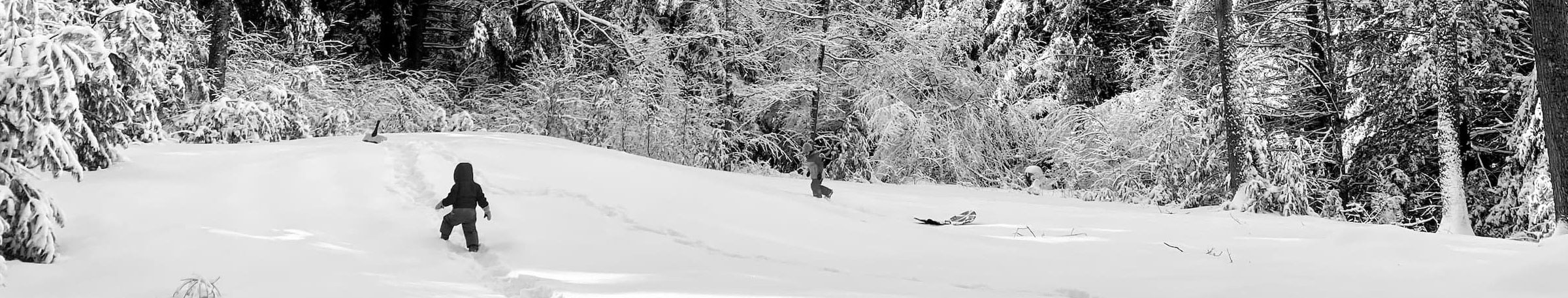 a little kid in a snowsuit walking up a path in the snow