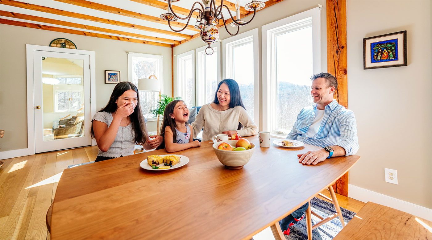 family laughing and eating breakfast. 