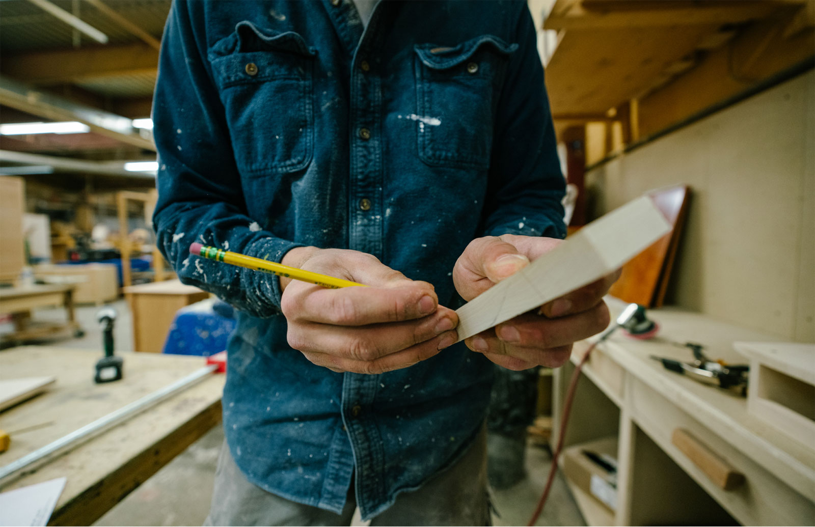 furniture craftsman marking piece of wood with pencil