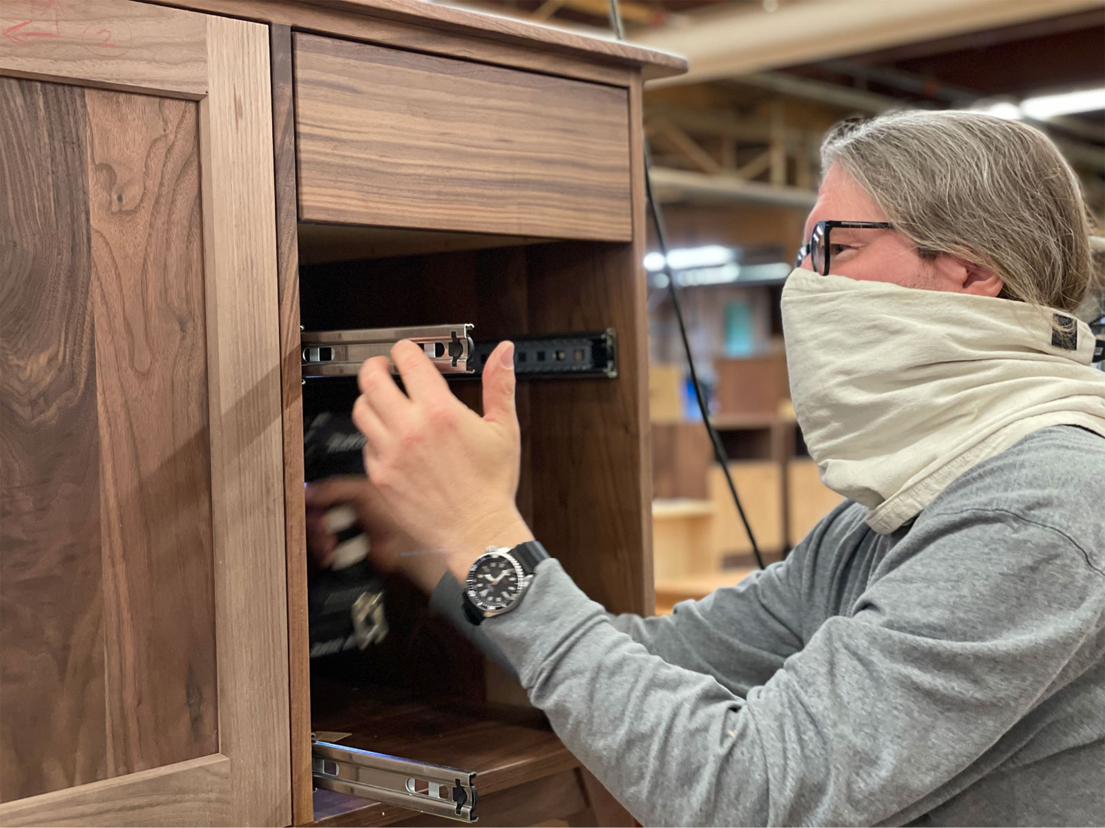 craftwoman installing metal drawer glides into a cabinet