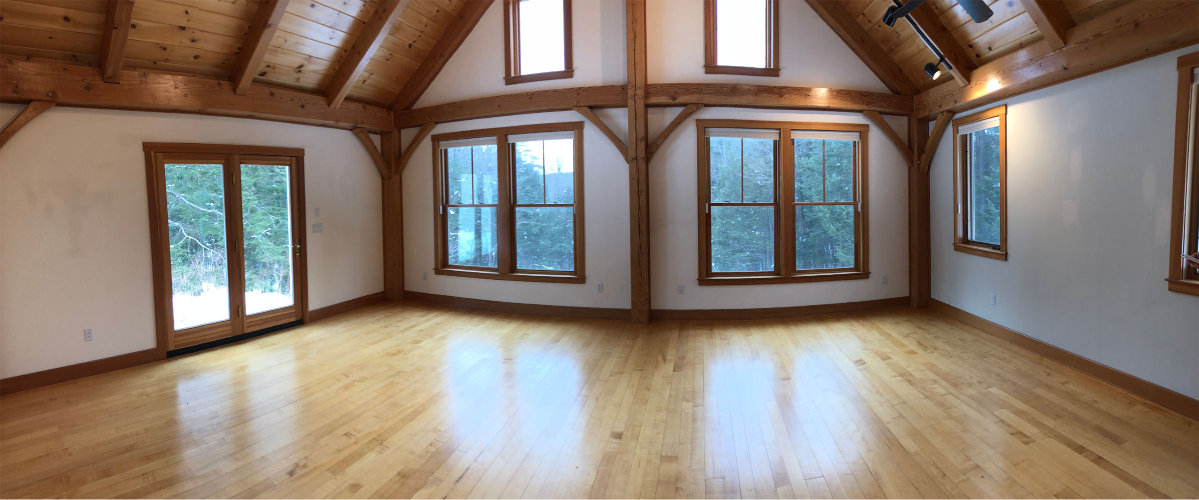 empty room in post and beam house with lots of windows