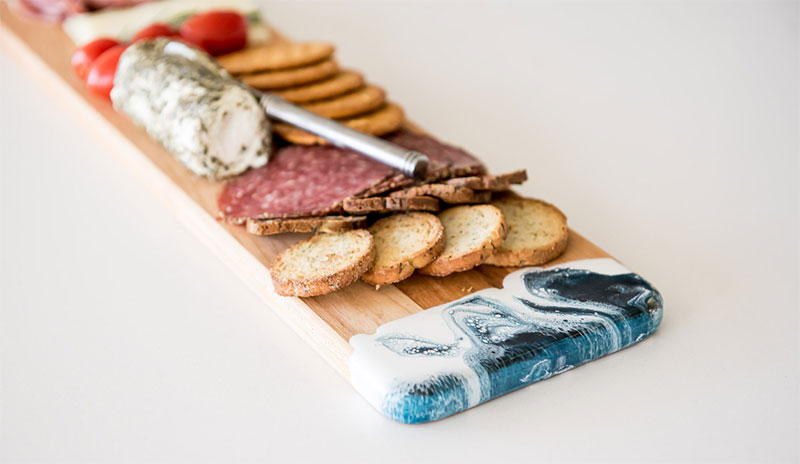 narrow cutting board with cheese, meat and crackers