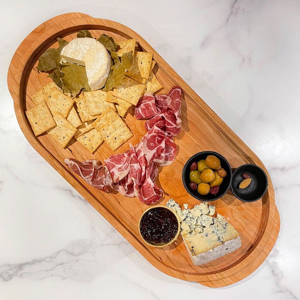 cherry serving tray with cheese, crackers, meat and oives
